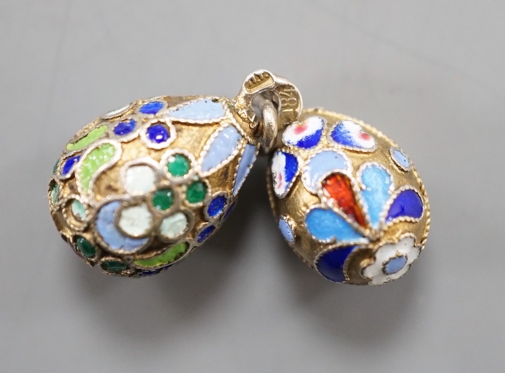 An early 20th century Russian 84 zolotnik and polychrome cloisonné enamel set egg pendant, maker's mark HT?, 17mm and a similar smaller egg pendant, maker's mark HM?.